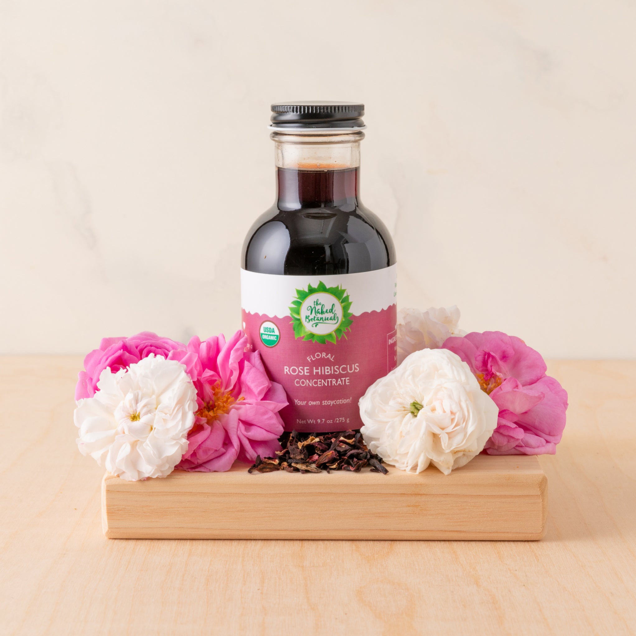 Bottle of Rose Hibiscus Concentrate with flowers on a wooden stand
