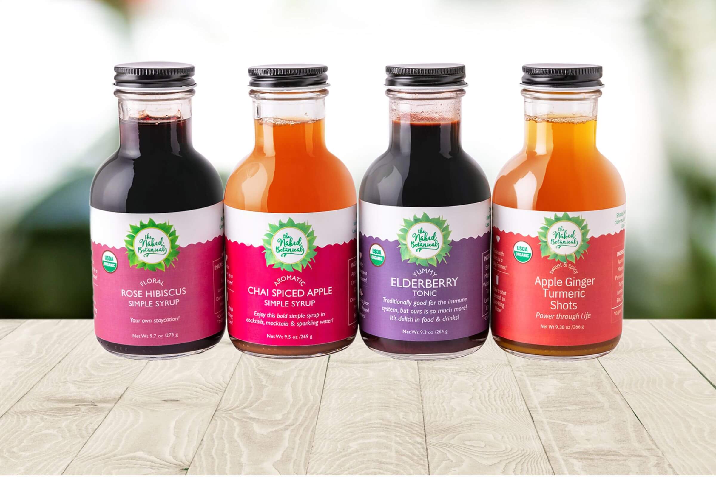 Four bottles of organic syrups on a wooden surface with a blurred natural background
